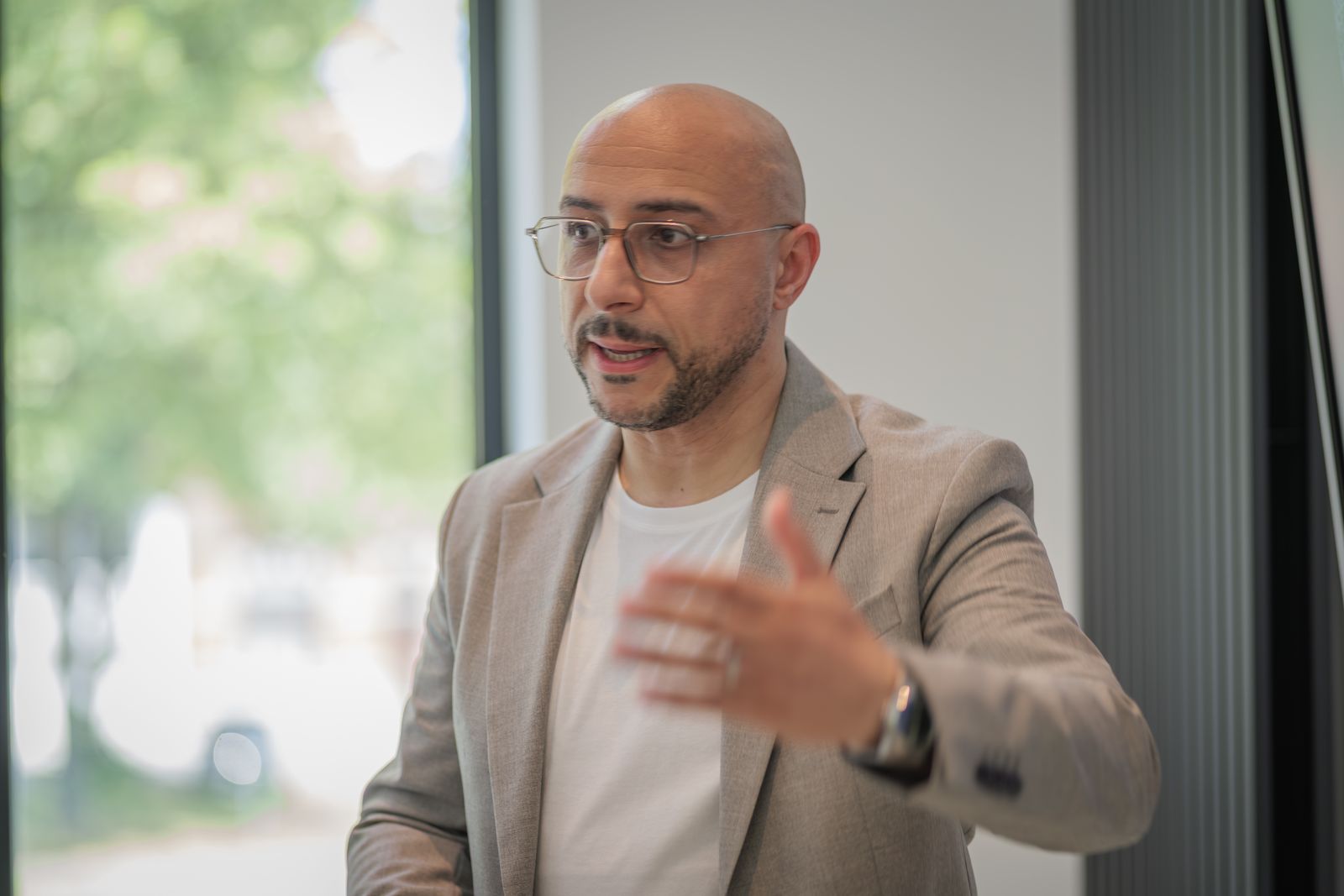 Salim Jebari en pleine explication, en veste beige, près d’une grande fenêtre
